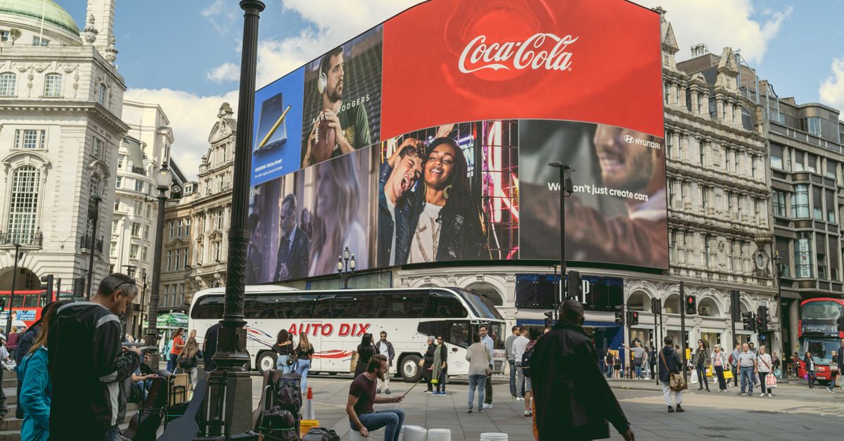 Tourists and buskers at Piccadilly Circus under iconic billboards in London, a center of urban life and commerce.